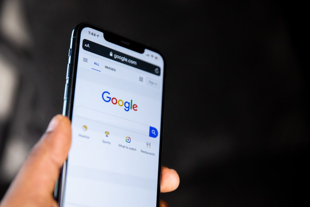 Google web app open on a modern smartphone, held in off-screen hand, black background